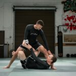 Two athletes grappling on the mat in a Brazilian jiu-jitsu match